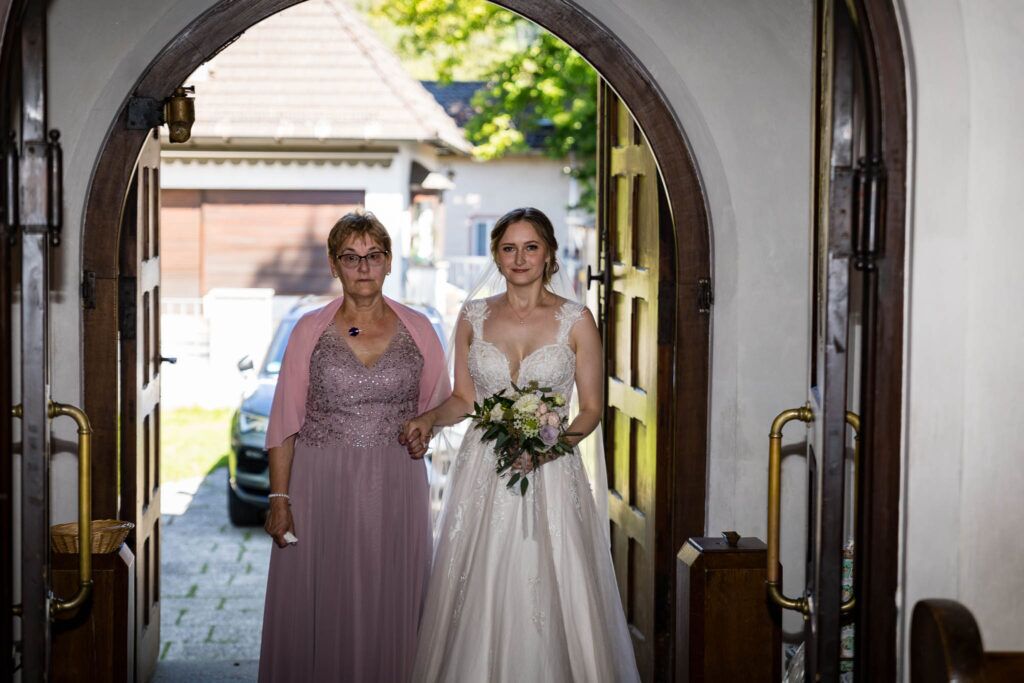 Jessica wird von Ihrer Mama zum Altar gebracht in der Kirche Wolfsratshausen auf ihrer Hochzeit in Wolfratshausen. Begleitet von den Hochzeitsfotografen München.